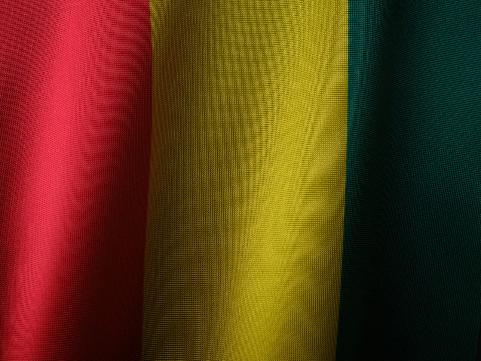 Close-up of the vibrant Guinea flag showing red, yellow, and green textile textures.