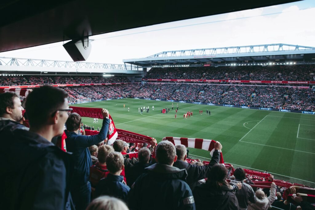 Fans cheer as players take the field at a vibrant football stadium, creating an electric atmosphere.